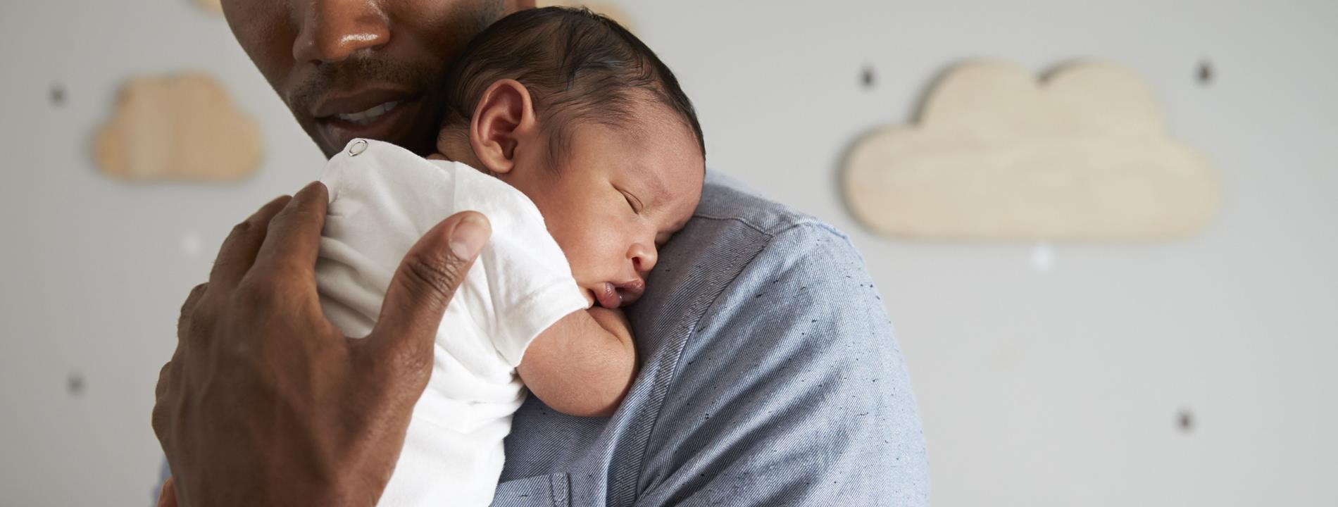 Gateshead Fertility: A father holds his baby to his chest as it sleeps in his arms.